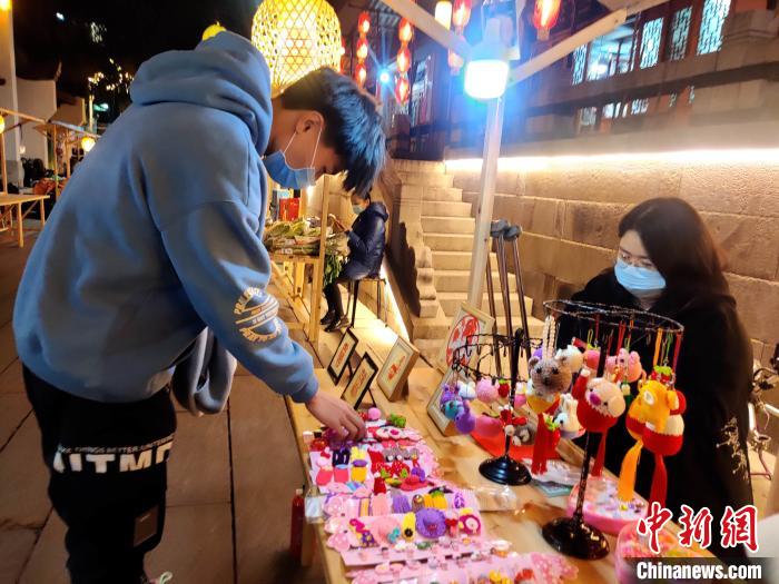 夜幕降臨，在福建省福州市鼓樓區(qū)西門的藏天園文化夜市內，同人助殘“愛·藝”手工坊負責人林琳正在“練攤”。　葉秋云 攝