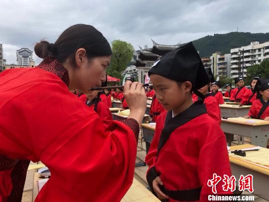 資料圖：在“點朱啟智”環(huán)節(jié)，先生在學(xué)童的額心點上朱砂，寓意孩子從此開啟智慧，目明心亮。曉東 攝