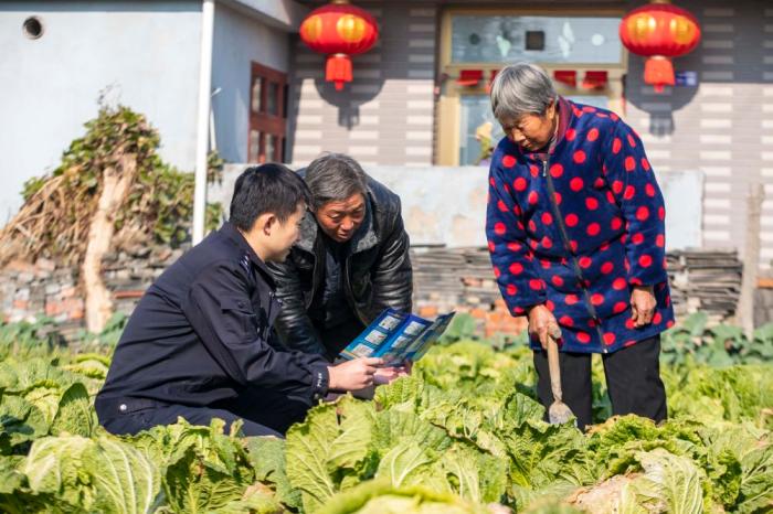 　江蘇省泰州市海陵區(qū)蘇陳派出所民警在蘇陳社區(qū)田間地頭向農(nóng)戶進(jìn)行普法宣傳(2021年12月4日攝)。新華社發(fā)(湯德宏 攝)