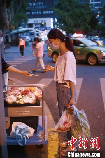 手提兩袋蔬菜的成都市民在選購鮮花。　受訪者供圖