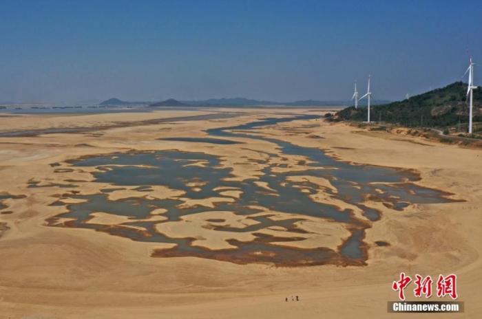 在江西省九江市都昌縣鄱陽(yáng)湖水域，干涸的湖床形成多個(gè)大小不同的水洼，幾名游客正在灘涂上行走。(資料圖) 劉占昆 　攝