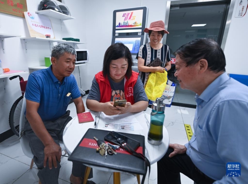 在浙江省杭州市臨安區(qū)玲瓏街道東山社區(qū)便民服務站，黨員志愿者幫助居民填寫公租房申請資料（2022年8月17日攝）。新華社記者 徐昱 攝