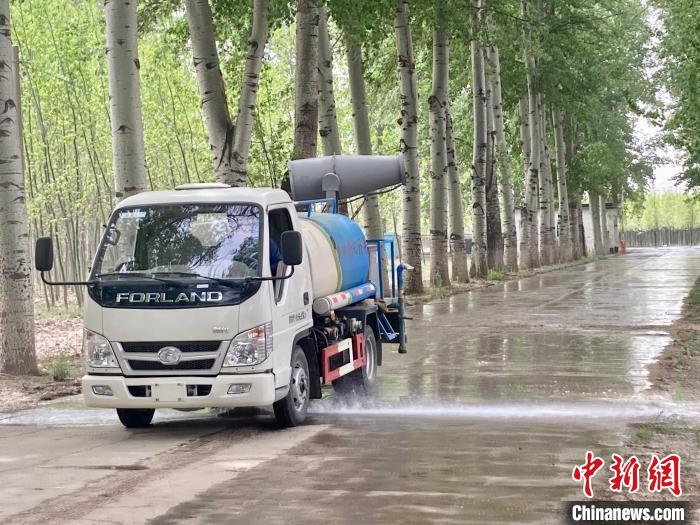 圖為灑水車在對(duì)地面進(jìn)行濕化，降低飄絮強(qiáng)度?！⌒戽?攝