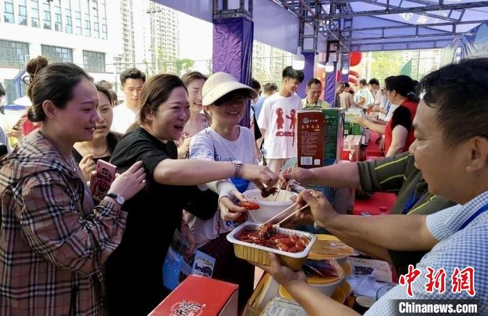 圖為江西南昌英雄城啤酒龍蝦燒烤節(jié)上，游客爭(zhēng)相品嘗鐵河小龍蝦預(yù)制菜?！⌒陆▍^(qū)融媒體中心供圖