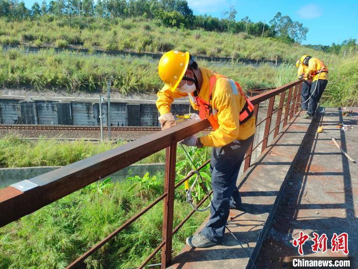 圖為高溫下南寧工務段橋梁工全副武裝對鐵路橋梁人行道欄桿打磨除銹?！●T博 攝