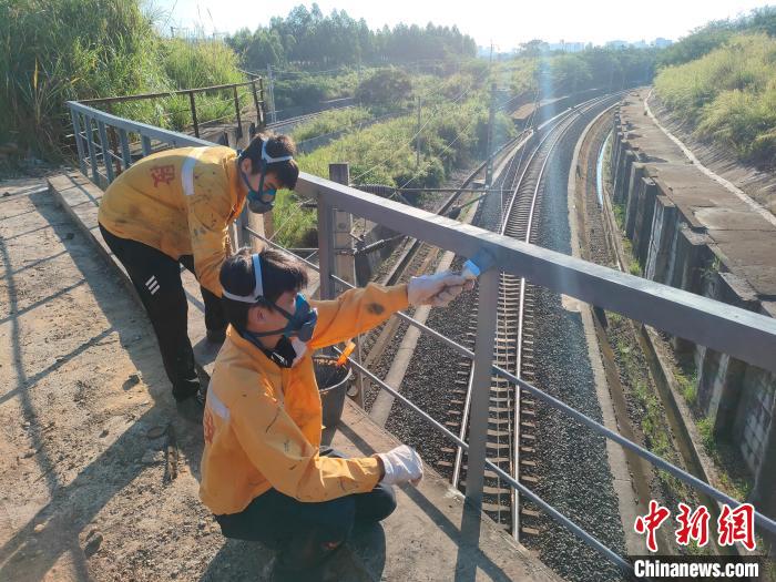 圖為高溫下南寧工務段橋梁工全副武裝對鐵路橋梁人行道欄桿打磨除銹?！●T博 攝